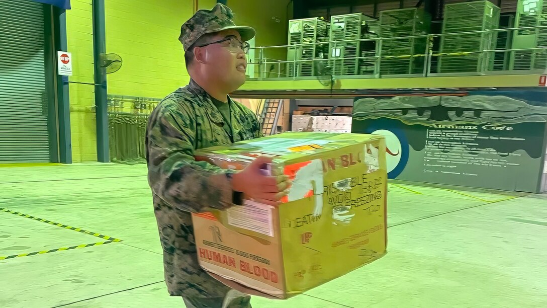 A U.S. Marine supporting Exercise Talisman Sabre 2023 carries a box of blood and plasma units prior to it being transported from Darwin to Townsville, Australia, July 23, 2023. Talisman Sabre is the largest bilateral military exercise between Australia and the United States advancing a free and open Indo-Pacific by strengthening relationships and interoperability among key allies and enhancing our collective capabilities to respond to a wide array of potential security concerns. (Photo courtesy of the U.S. Army/Released)