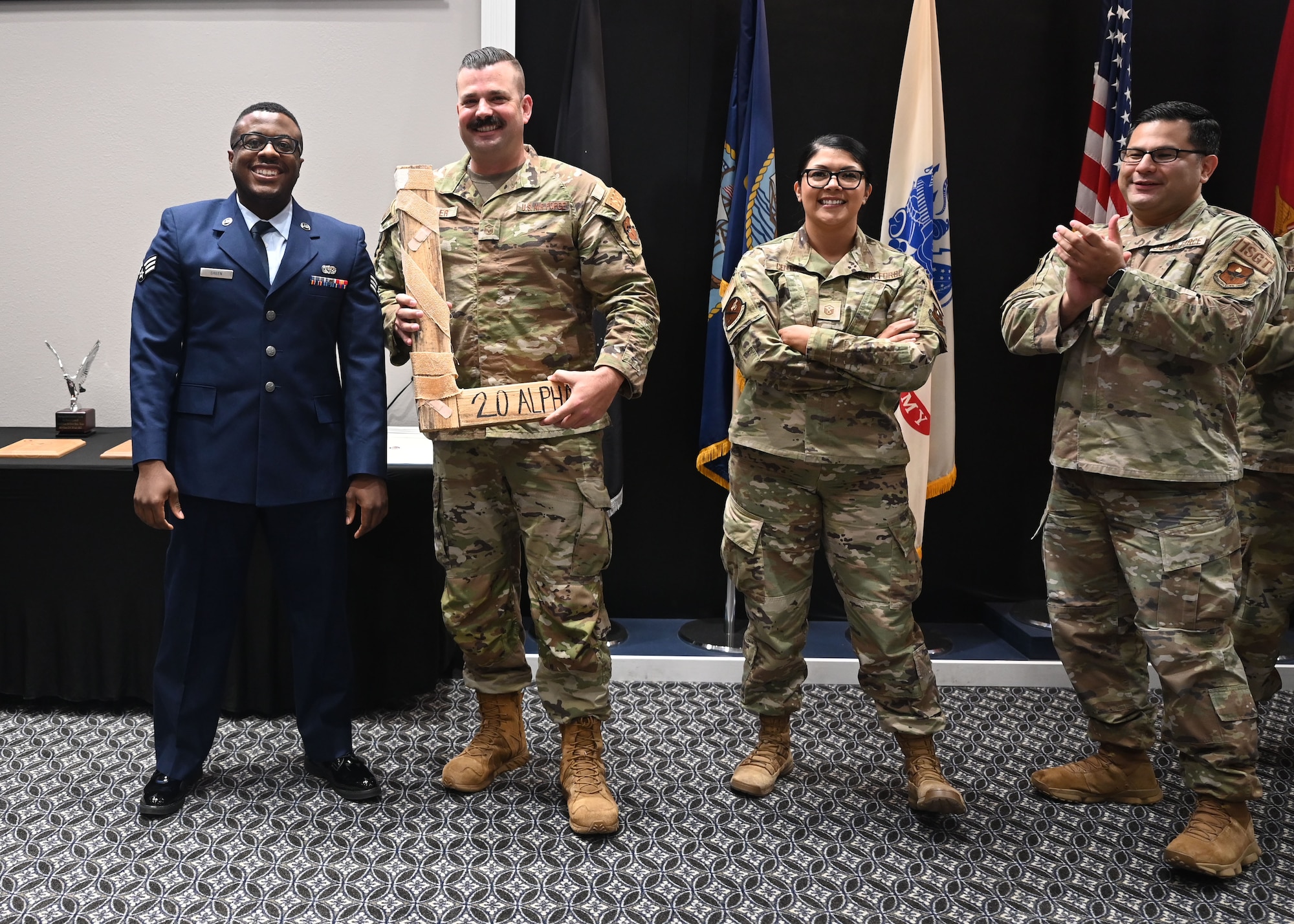 U.S. Air Force Senior Airman Steven Green II, Class 23-E Airman Leadership School graduate, presents the “L” to a group of first sergeants belonging to the 17th Training Wing at the Class 23-E ALS graduation in the Powell Event Center, Goodfellow Air Force Base, Texas, July 20, 2023. Every ALS class plays a volleyball game with the first sergeants and the winning team presents the “L” to the losing team at graduation. (U.S. Air Force photo by Senior Airman Ethan Sherwood)