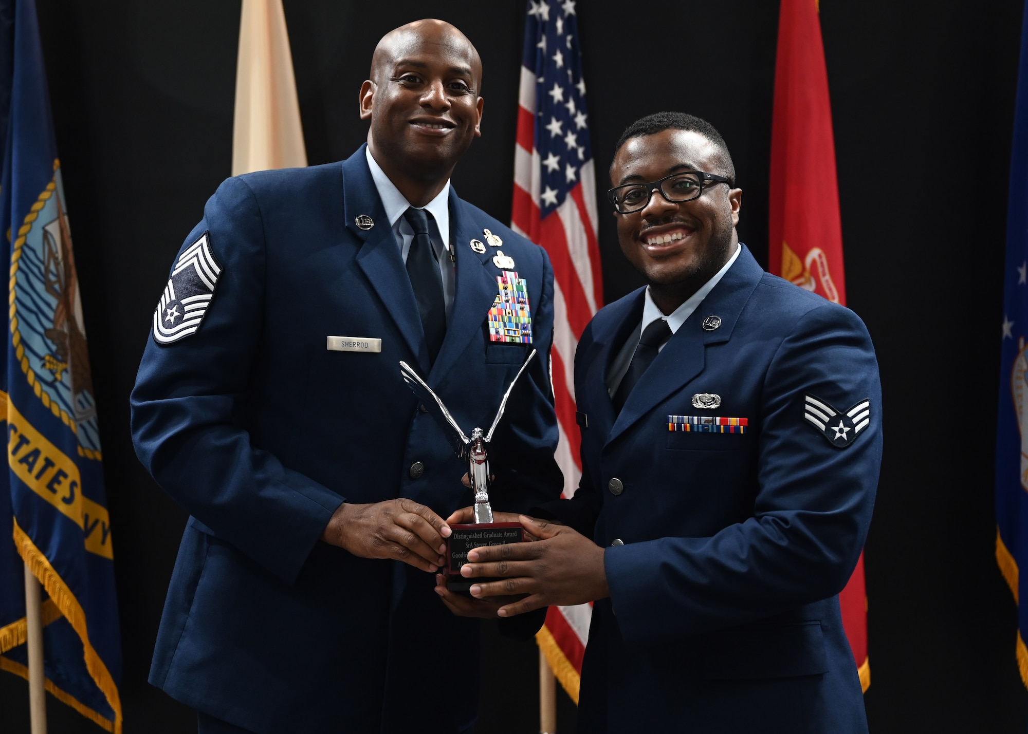 U.S. Air Force Chief Master Sgt. Derrick Sherrod, 17th Mission Support Group senior enlisted leader, presents the Distinguished Graduate Award to Senior Airman Steven Green II, Class 23-E Airman Leadership School graduate, at the Class 23-E ALS graduation in the Powell Event Center, Goodfellow Air Force Base, Texas, July 20, 2023. The Distinguished Graduate Award recognizes the student who is in the top 10 percent of their class based on performance tasks, peer stratifications, and the capstone exercise. (U.S. Air Force photo by Senior Airman Ethan Sherwood)