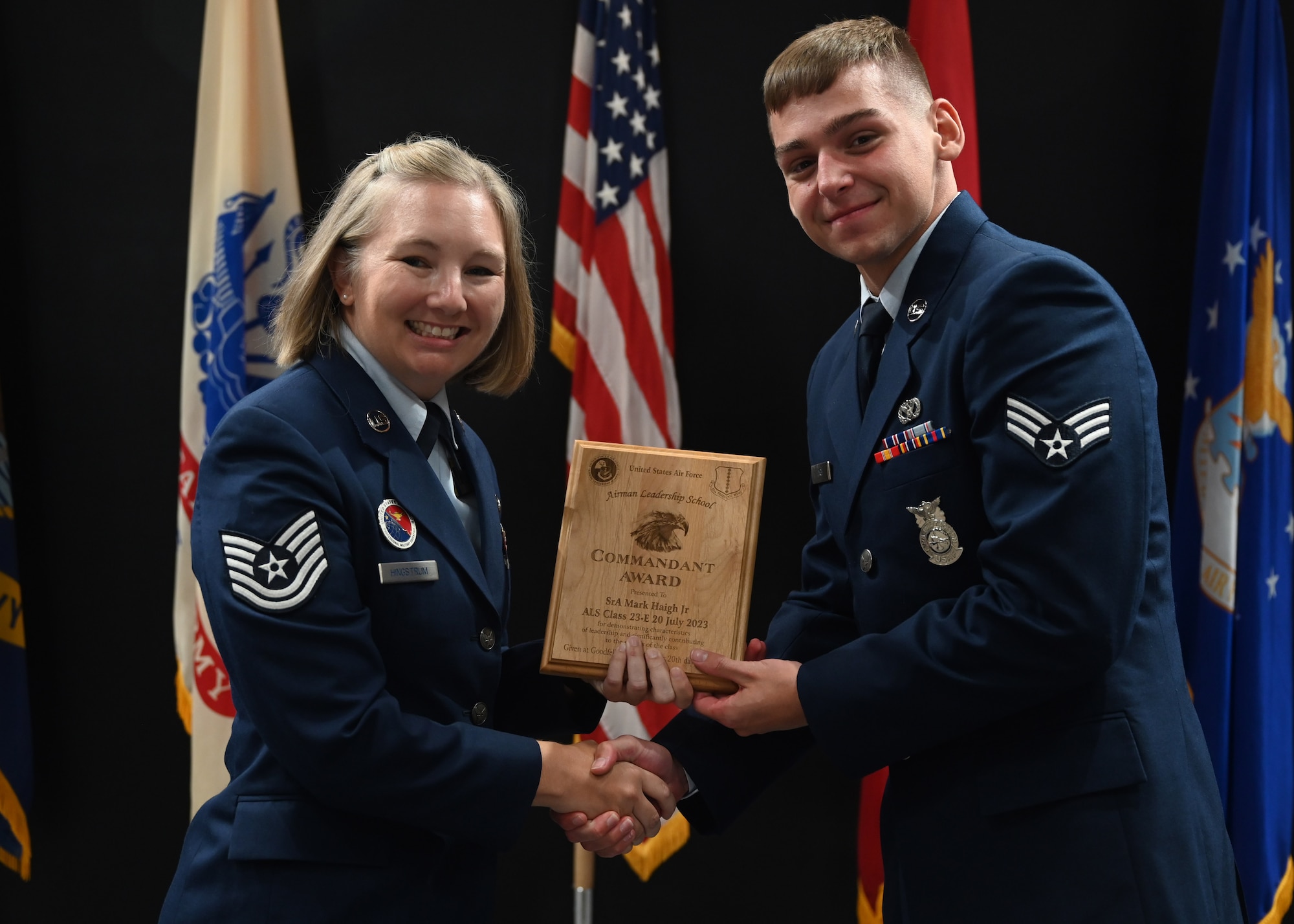 U.S. Air Force Tech. Sgt. Kristin Hingstrum, Airman Leadership School commandant, presents the Commandant Award to Senior Airman Mark Haigh Jr., Class 23-E Airman Leadership School graduate, at the Class 23-E ALS graduation in the Powell Event Center, Goodfellow Air Force Base, Texas, July 20, 2023. The Commandant Award is presented to the person who demonstrated superior leadership as identified by their peers and the ALS staff. (U.S. Air Force photo by Senior Airman Ethan Sherwood)