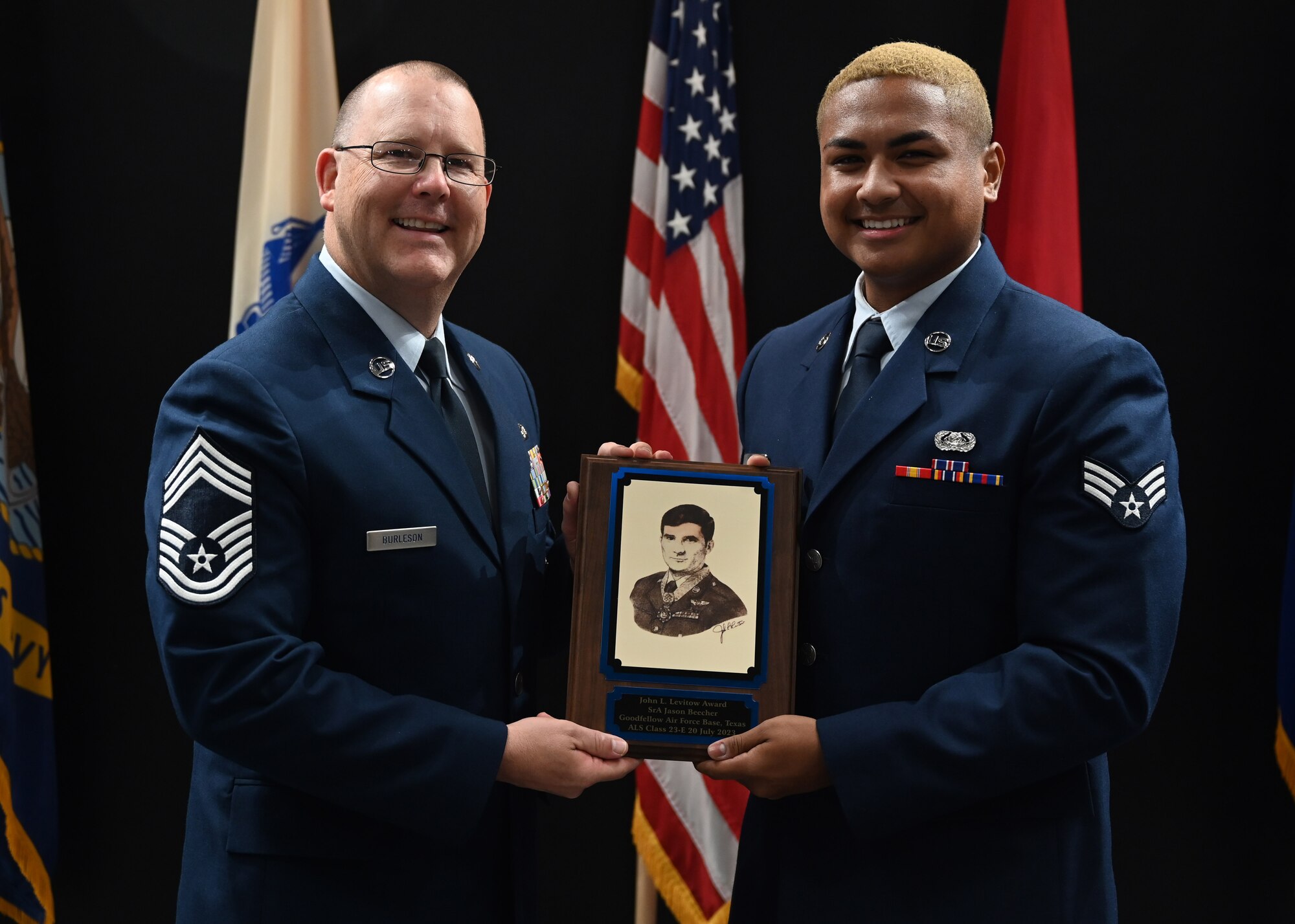 U.S. Air Force Chief Master Sgt. Anthony Burleson, 47th Mission Support Group superintendent, presents the John L. Levitow Award to Senior Airman Jason Beecher, Class 23-E Airman Leadership School graduate, at the Class 23-E ALS graduation in the Powell Event Center, Goodfellow Air Force Base, Texas, July 20, 2023. The John L. Levitow Award is the highest award offered at ALS; it is based upon all performance tasks, peer stratifications, and the capstone exercise. (U.S. Air Force photo by Senior Airman Ethan Sherwood)