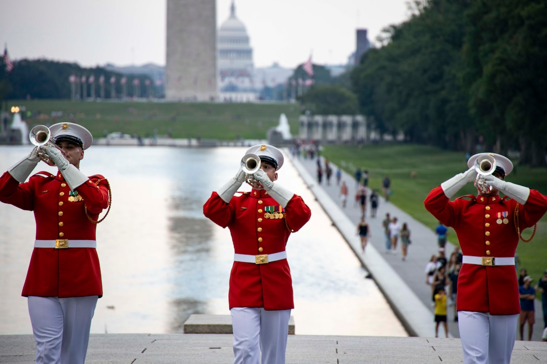 Three Marines in formal uniforms play instruments on the steps of the Lincoln Memorial.