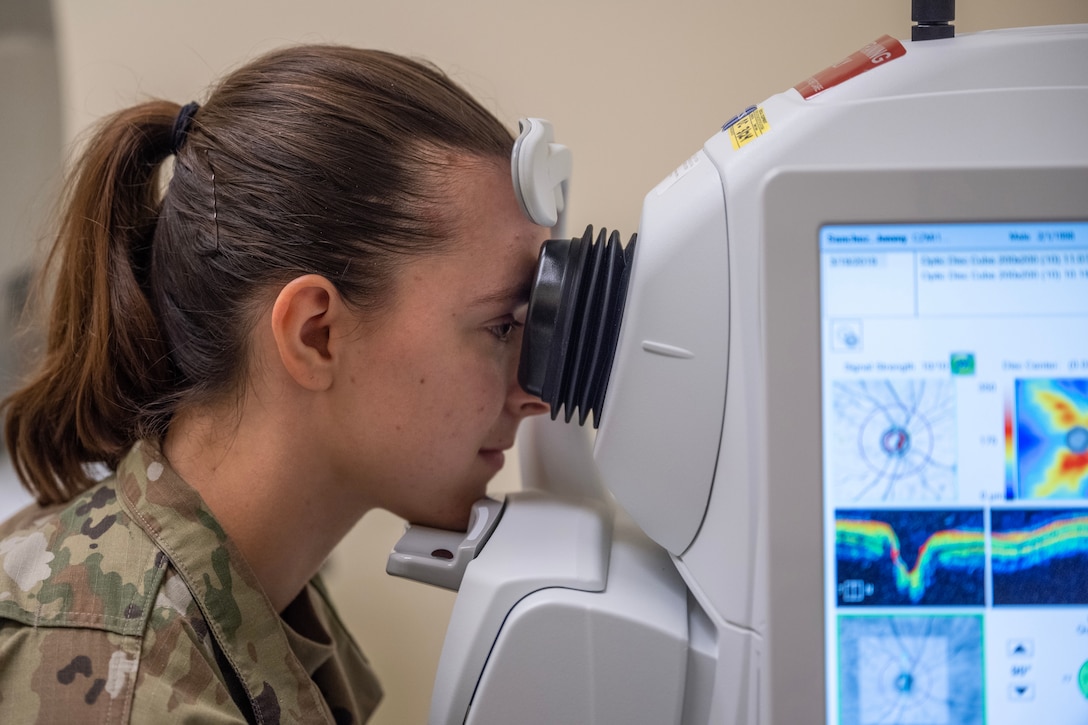 An airman looks into an optical device.