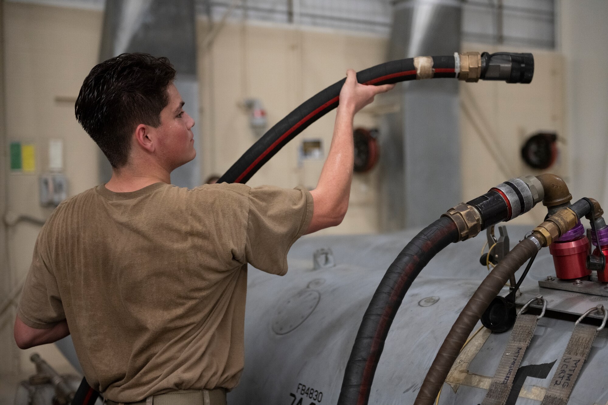 A man holding a hose raising it above his shoulder passing it to someone off to the right of the photo.