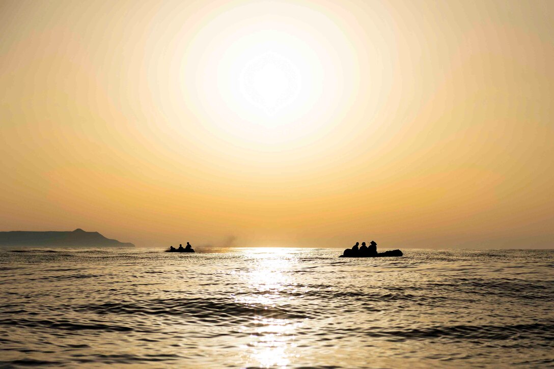 Marines travel through a body of water in two combat rubber raiding crafts.