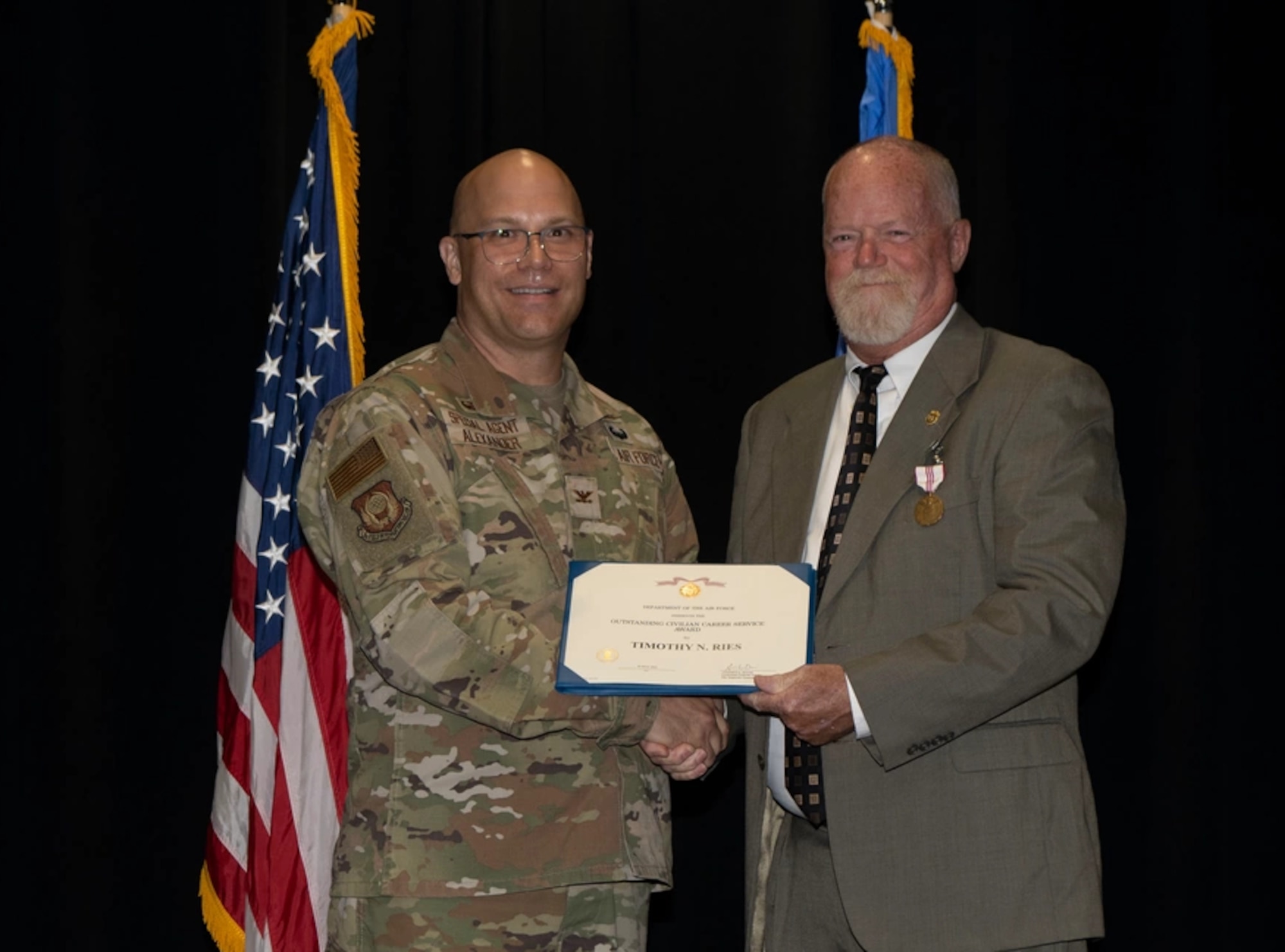 Col. Brian Alexander, OSI 3rd Field Investigations Region commander, presents Special Agent Timothy Ries with an Outstanding Civilian Career Award during his retirement ceremony at MacDill Air Force Base, Florida, July 27, 2023. After retiring from active duty service in 2000 as a lieutenant colonel, Ries went on to serve an additional 23 years as a civilian special agent with the Office of Special Investigations.
