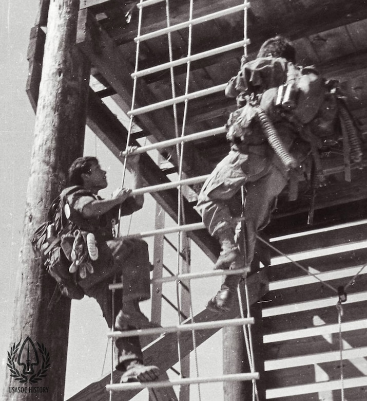 Two men scale a rope ladder