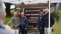 Maj. Gen. Torrence Saxe, adjutant general of 
the Alaska National Guard and commissioner 
of the Department of Military and Veterans 
Affairs, stands with friends and brothers in 
arms of Specialist Four Harmon in front of the 
new Kodiak Reediness Center sign July 27, 
2023, in Kodiak, Alaska.