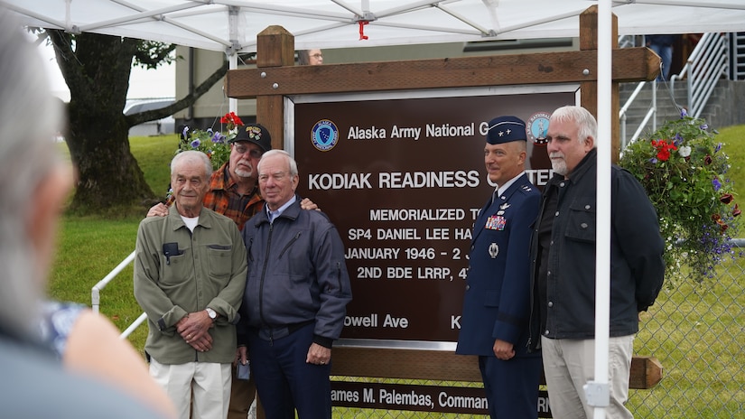 Maj. Gen. Torrence Saxe, adjutant general of 
the Alaska National Guard and commissioner 
of the Department of Military and Veterans 
Affairs, stands with friends and brothers in 
arms of Specialist Four Harmon in front of the 
new Kodiak Reediness Center sign July 27, 
2023, in Kodiak, Alaska.