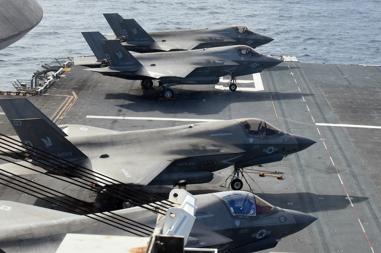A row of Marine jets are parked on a vessel.