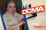 Man wearing glasses has on a brown DCMA shirt