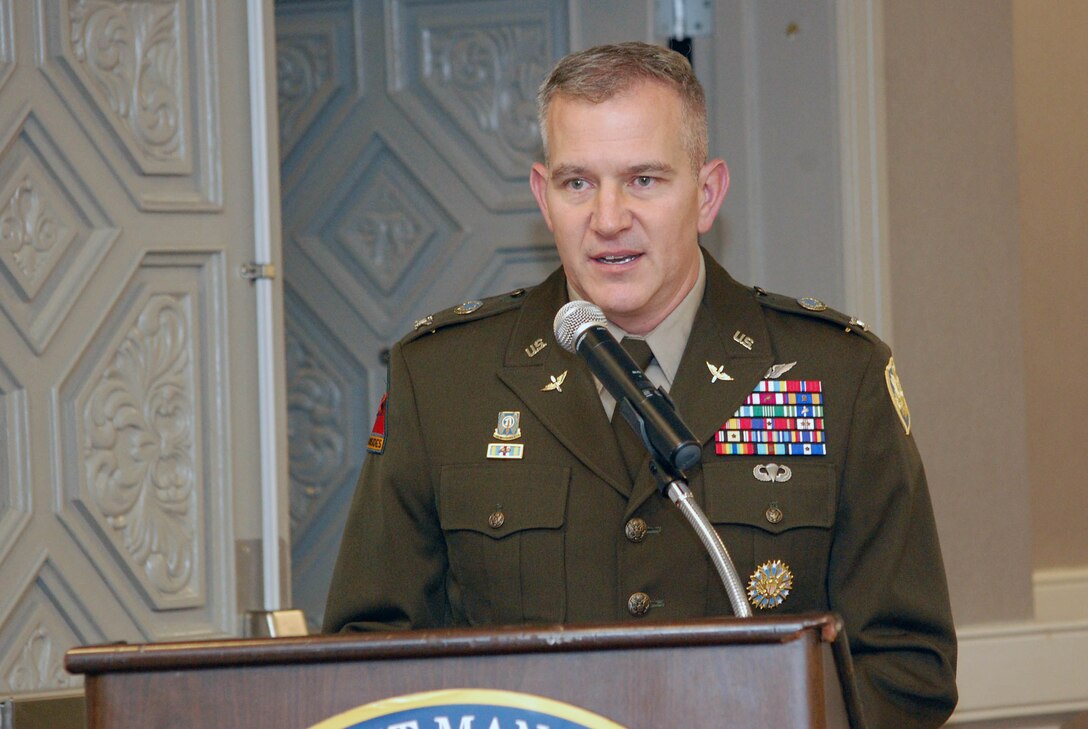 Man speaking behind a podium wearing his military uniform