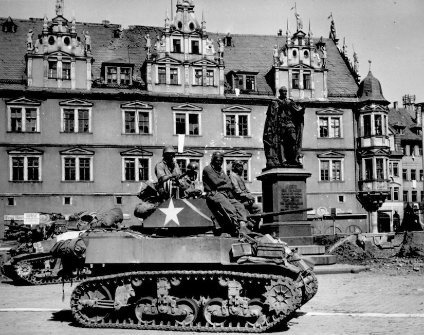 A tank rolls through a town.
