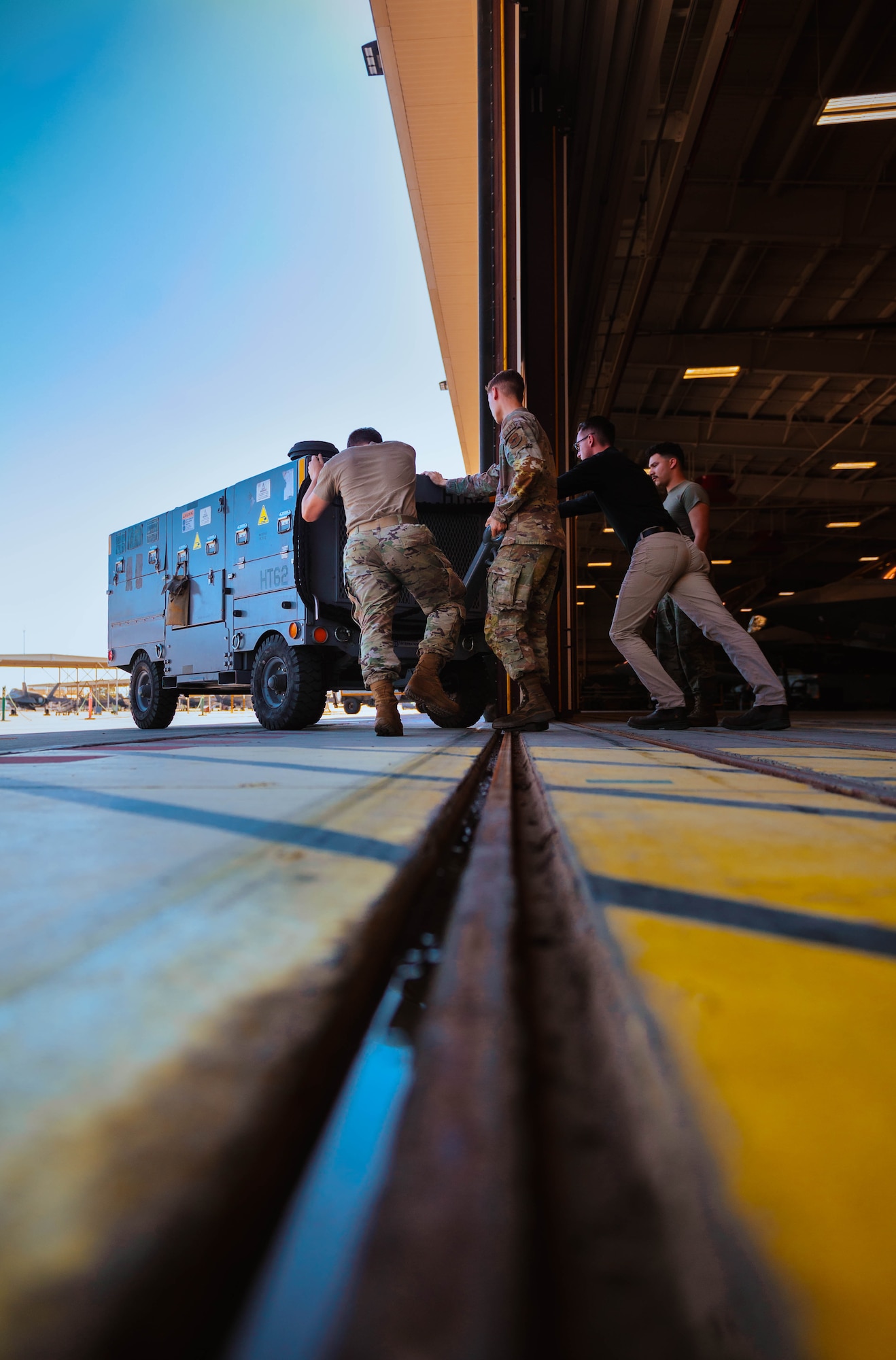 Nelson Bergemann (second from right), 56th Maintenance Group Air Force Engineering Technical Services avionics senior equipment specialist and U.S. Air Force Airmen assigned to the 308th Fighter Squadron, push a diesel hydraulic cart.