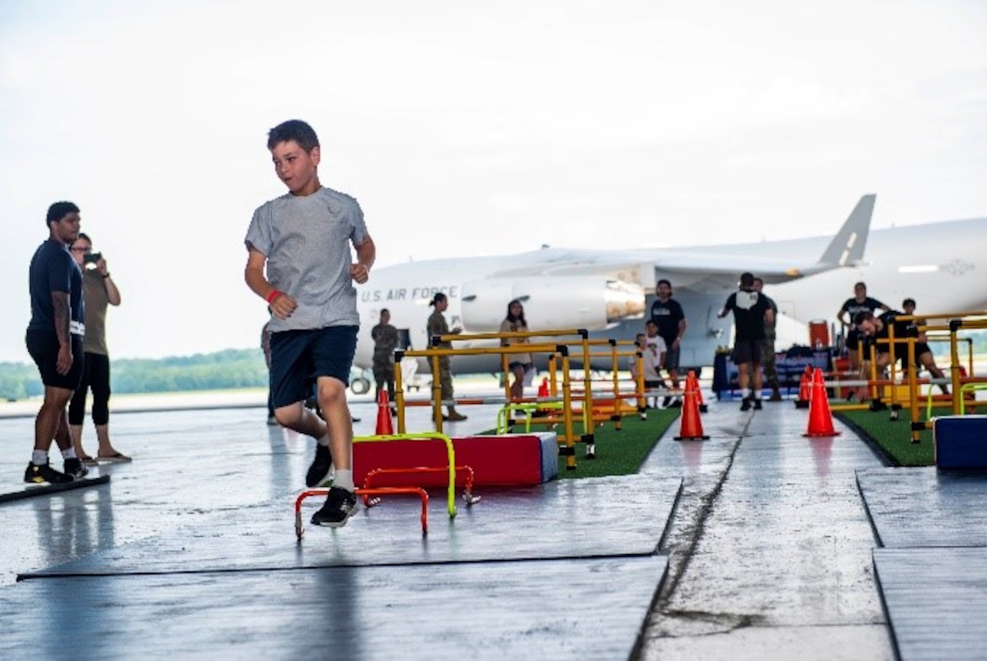 A child participating in Operation KUDOS runs out the end of an obstacle course in Hangar 206 on Wright-Patterson Air Force Base, Ohio, July 28, 2023. The Kids Understanding Deployment Operations event is meant to teach children in military families about deployments through engaging activities. (U.S. Air Force photo by Airman 1st Class James Johnson)