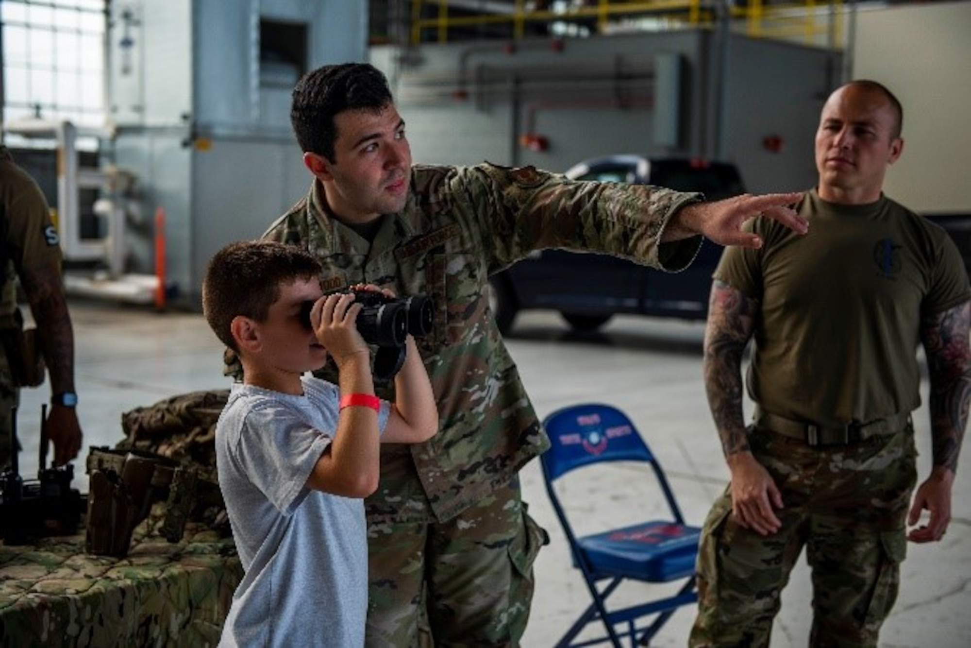 An 88th Security Forces Squadron Airman instructs a child using binoculars as part of Operation KUDOS on July 28 at Wright-Patterson Air Force Base, Ohio. The annual Kids Understanding Deployment Operations event is meant to teach children in military families about deployments through engaging activities. (U.S. Air Force photo by Airman 1st Class James Johnson)