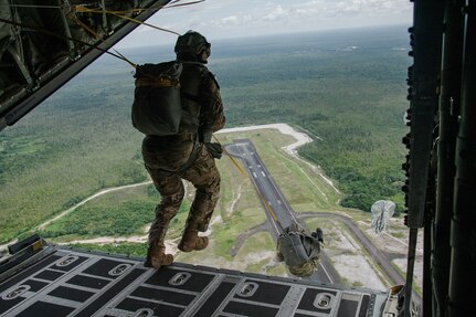 U.S. Airmen jump from the back of a C-130 with parachutes