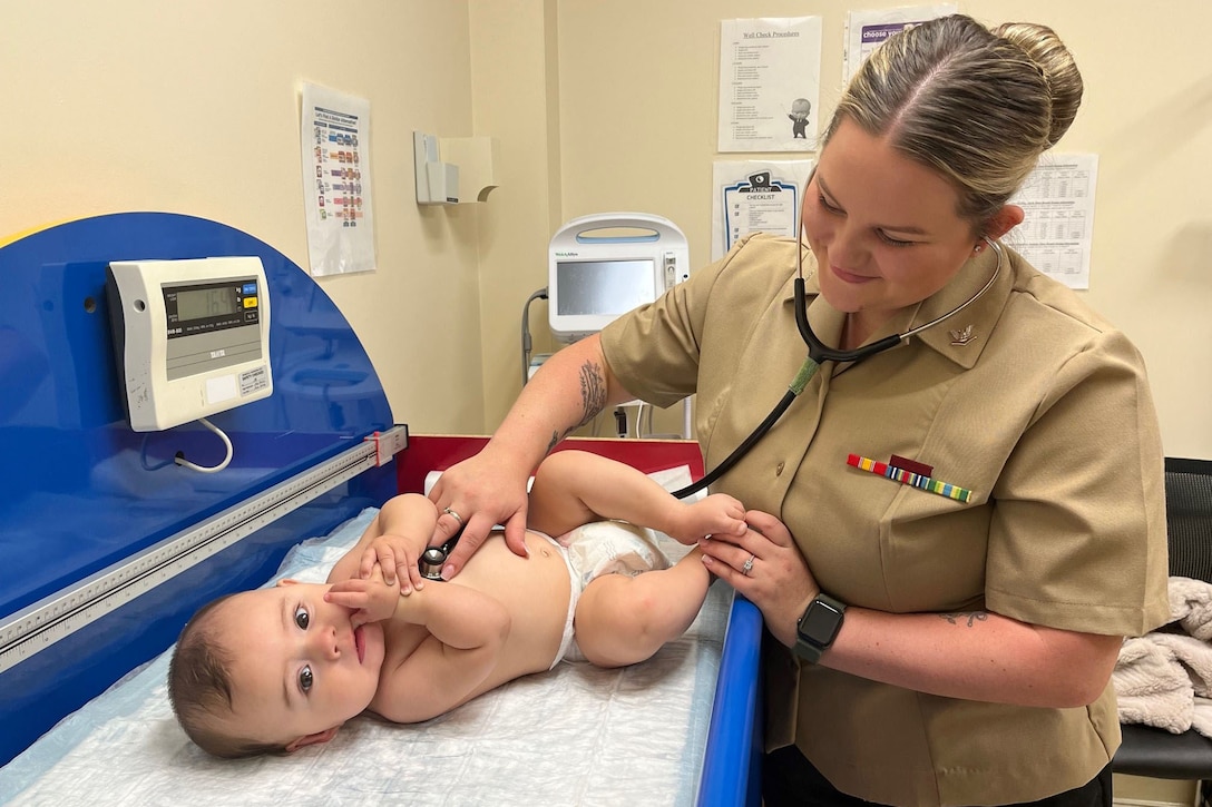 A sailor checks a baby's heartbeat.