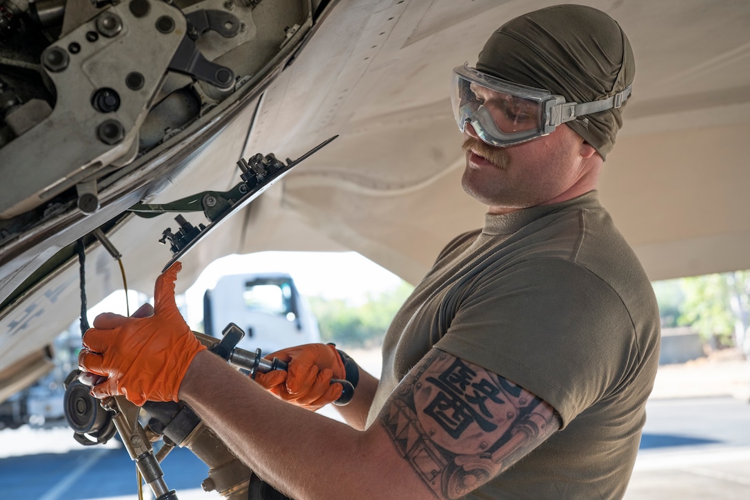 Man holds a fuel pump to an aircraft