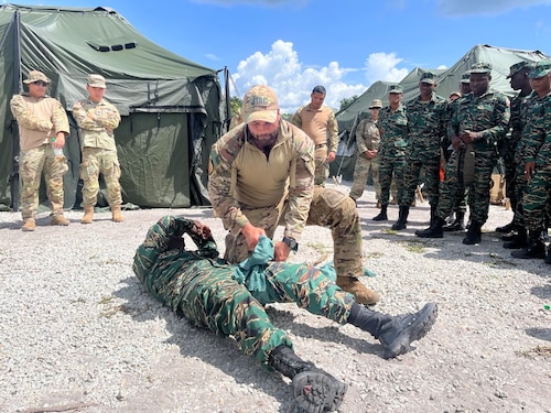 U.S. Air Force Tech. Sgt. Scott Palelei, 137th Special Operations Wing tactical air control party specialist, Oklahoma Air National Guard, applies a tourniquet to a member of the Guyana Defense Force during tactical combat casualty training held at Camp Seweyo, Guyana, for Tradewinds 23 exercise July 16, 2023.