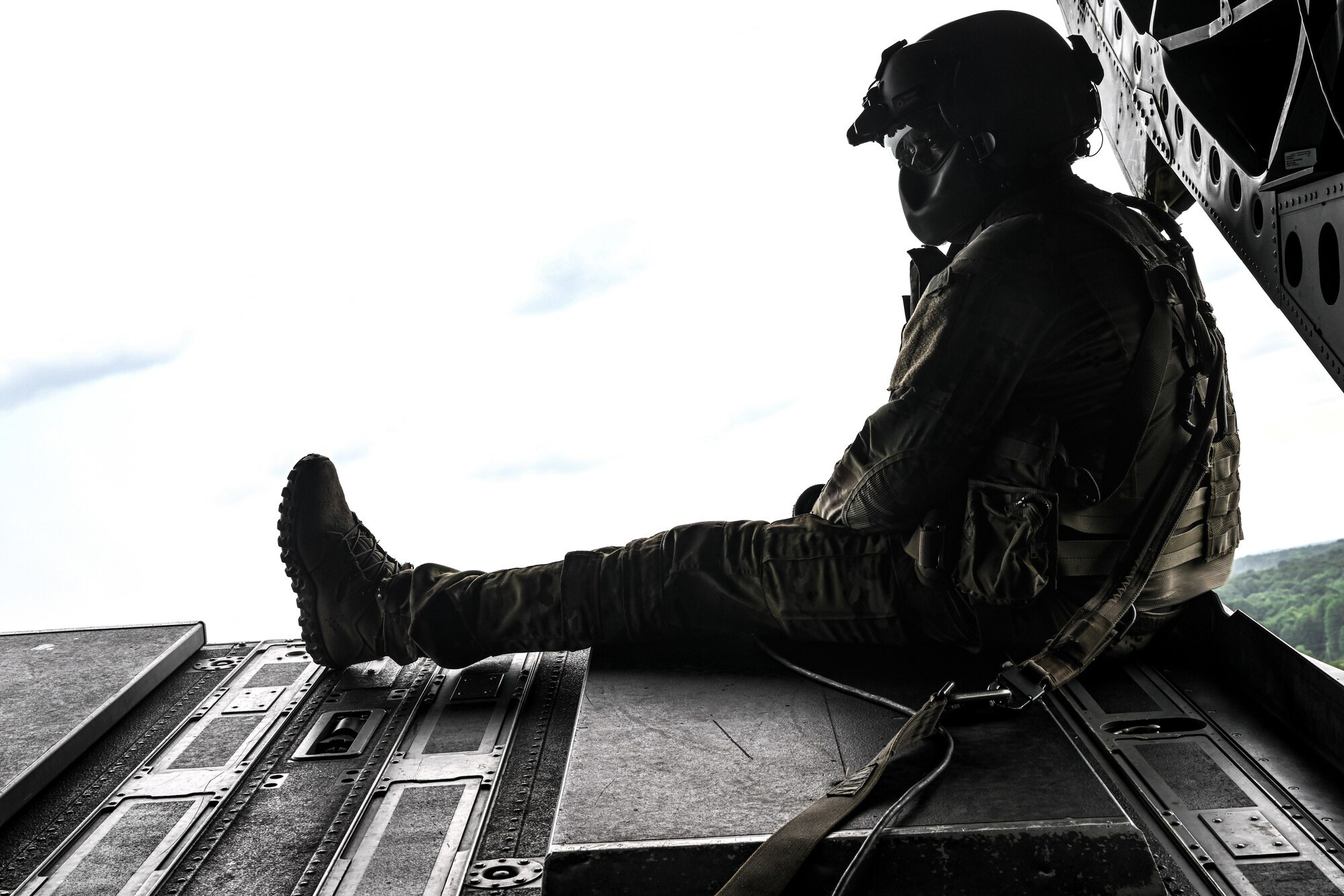 An Ohio National Guard aircrew member sits on the ramp door of a CH-47 Chinook helicopter on July 25, 2023, while flying over Camp James A. Garfield Joint Military Training Center, Ohio.