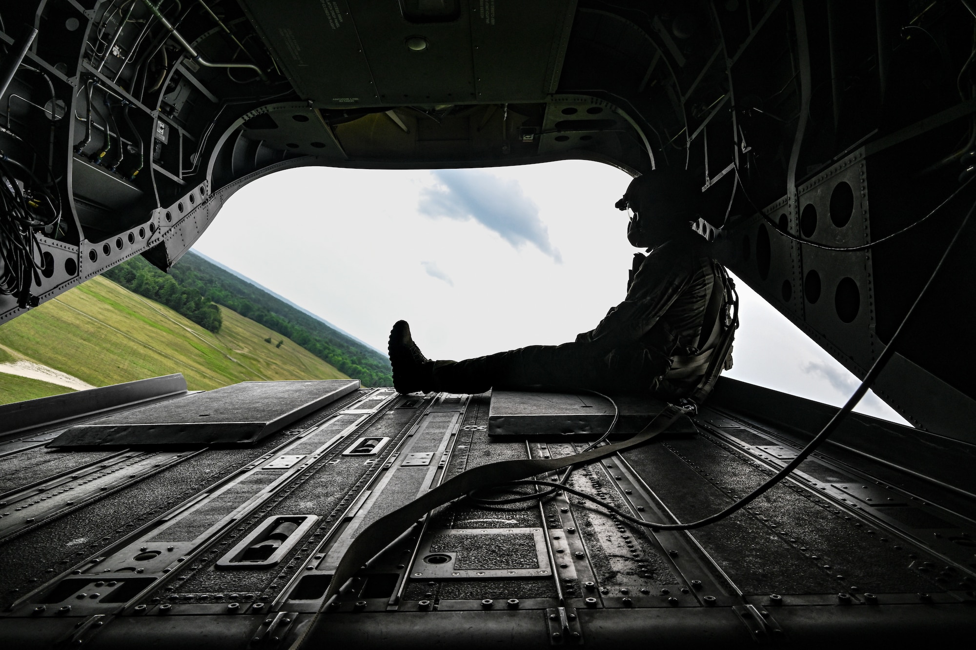 An Ohio National Guard aircrew member sits on the ramp door of a CH-47 Chinook helicopter on July 25, 2023, while flying over Camp James A. Garfield Joint Military Training Center, Ohio.