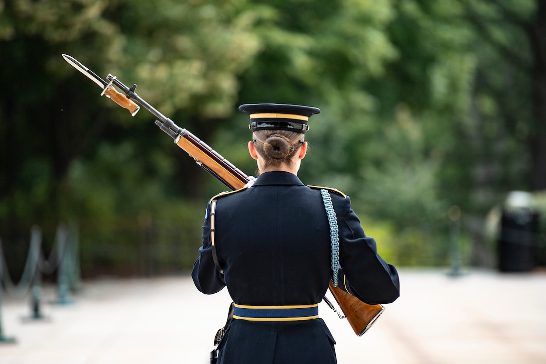 A tomb guard is pictured from behind, in uniform, holding a weapon.