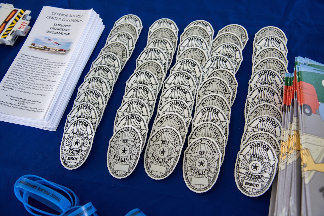 Police badge shaped stickers in black and white on a table with a blue tablecloth.
