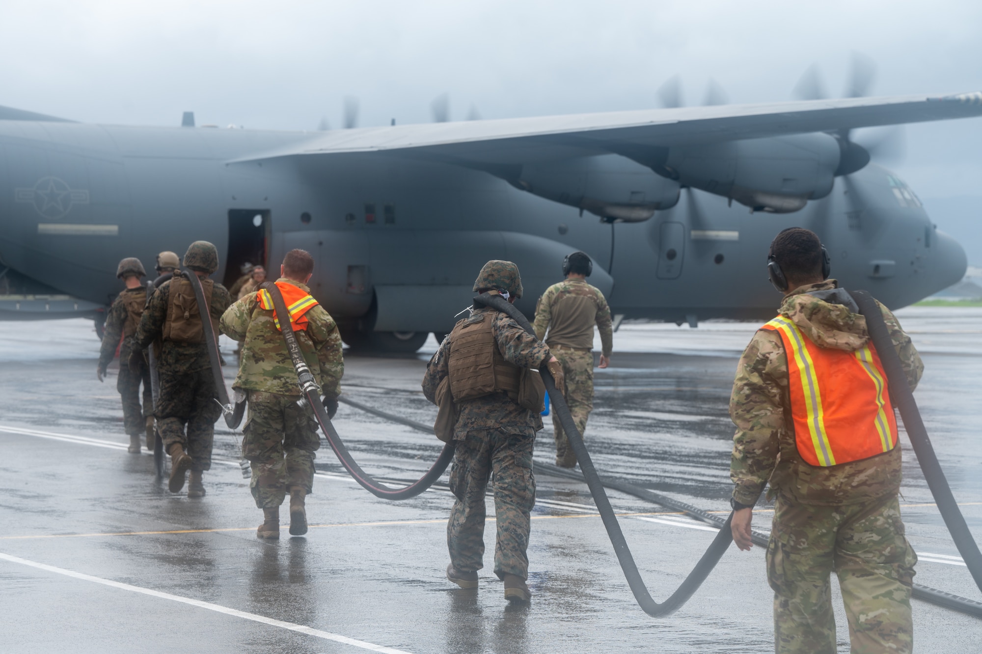 U.S. Air Force Airmen, assigned to Davis-Monthan Air Force Base, Arizona and Marine Corps Marines, assigned to Marine Wing Support Squadron 373, pick up a fuel line together during a forward arming and refueling exercise for Cope Thunder 23-2  at Subic Bay International Airport, Philippines, July 15, 2023. Cope Thunder 23-2 provided valuable training to aircrews allowing joint foreign forces to work together and improve interoperability. (U.S. Air Force photo by Senior Airman Vaughn Weber)