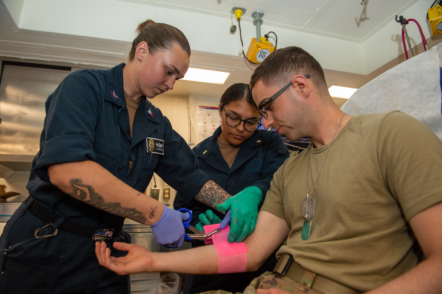 SAN DIEGO (July 26, 2023) Ensign Ilana Silva, a native of El Centro, California, observes as Hospital Corpsman 2nd Class Amanda Eldridge, a native of Nashville, Tennessee, demonstrates how to apply gauze to a wound during training in the medical bay of USS Boxer (LHD 4). Silva is one of eight second-year medical students from the Army, Air Force and Navy enrolled at the Uniformed Services University of the Health Sciences (USU) who spent two weeks onboard USS Boxer (LHD 4) training in operational medicine (OPMED). Boxer is a Wasp-class amphibious assault ship homeported in San Diego. (U.S. Navy photo by Mass Communication Specialist 2nd Class Connor Burns)