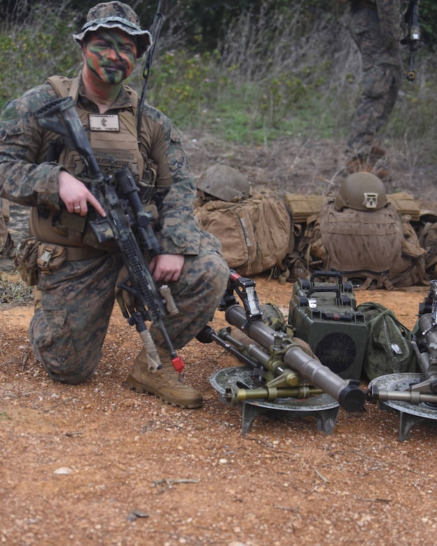 A uniformed service member poses for a photo while holding his weapon.