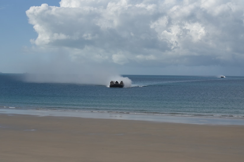 A military landing craft propels through the water.