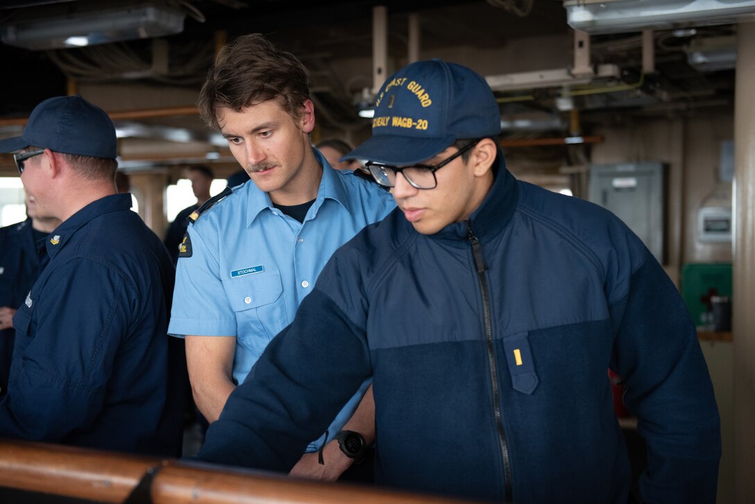Ensign Zane Miagany, a Coast Guard Cutter Healy (WAGB 20) marine science officer, demonstrates use of bridge equipment to an officer from the Canadian Coast Guard Ship Sir Wilfrid Laurier, in the Beaufort Sea, July 28, 2023. The crews conducted a passenger exchange with the CCGS Sir Wilfrid Laurier off the coast of Utqiagvik, Alaska. (Coast Guard photo by Petty Officer 3rd Class Briana Carter)