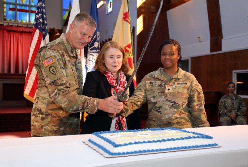 Three people cut a cake in a church.