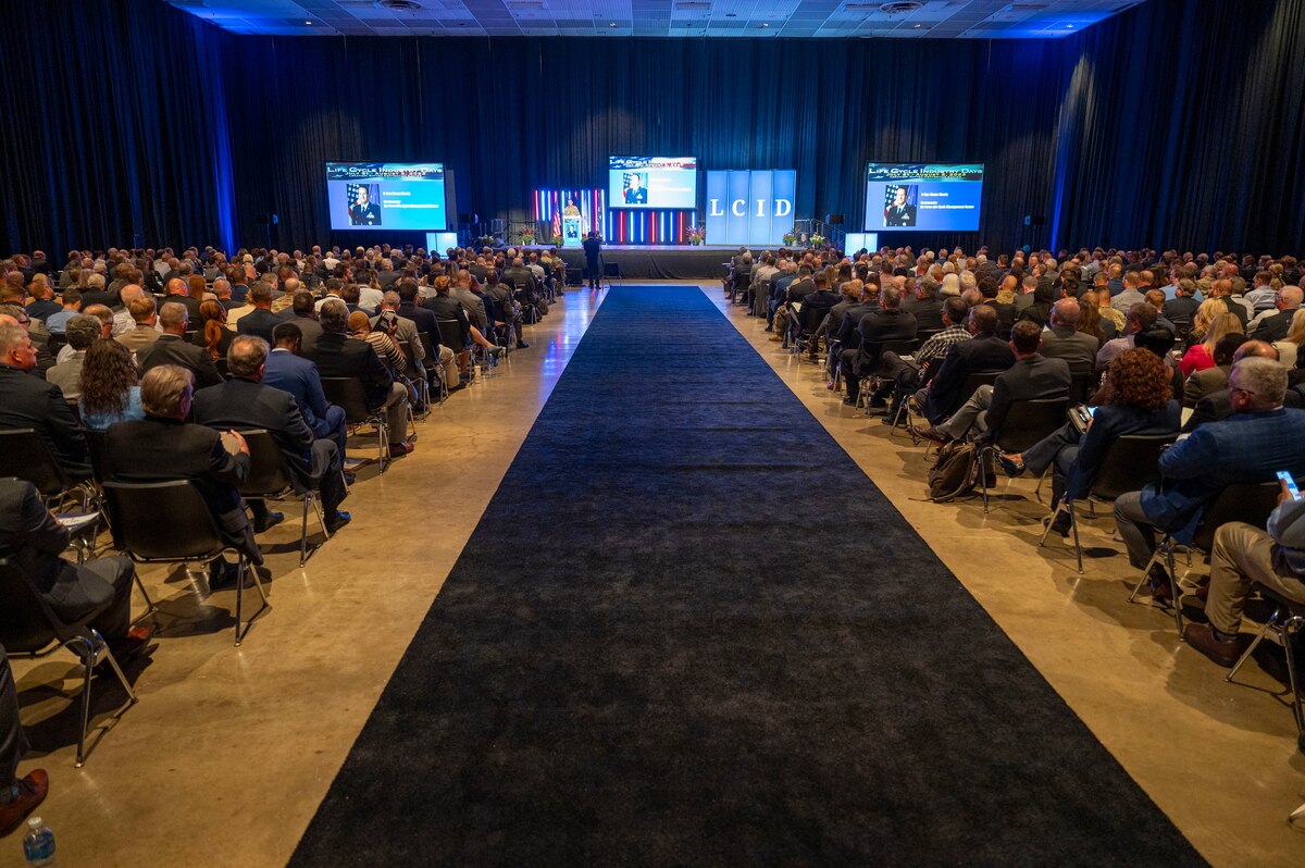 Individuals seated, watching a speaker on stage.