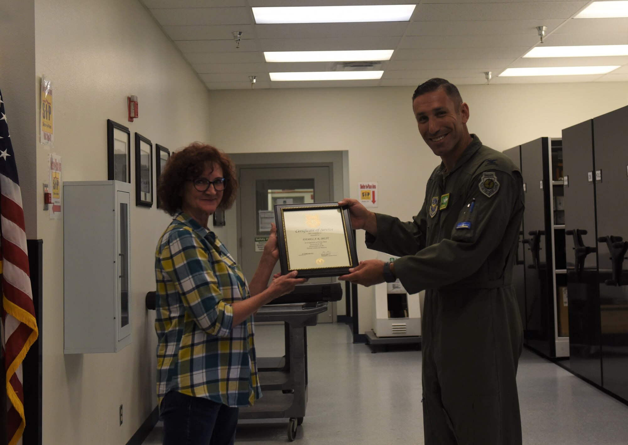 U.S. Air Force Col. David Morales, 62d Airlift Wing deputy commander, presents Pamela Best, electronic mechanic with the 62d Maintenance Squadron, with a certificate of service at Joint Base Lewis-McChord, Washington, July 26, 2023. Best joined the Air Force in 1983 as an avionic inertial RADAR navigation specialist. This month she celebrates 40 years of combined duty and civilian service with the Air Force. (U.S. Air Force photo by Airman 1st Class Kylee Tyus)