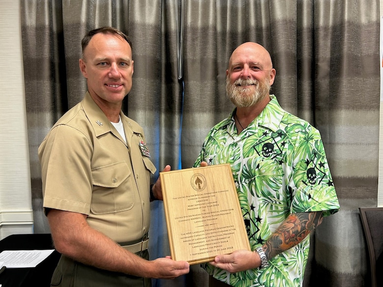 U.S. Marine Corps Col. Ronald Norris, commanding officer, Marine Raider Regiment, Marine Forces Special Operations Command, and Edward Walsh, command language program manager, MRR, MARSOC, pose for a photo with the 2023 U.S. Special Operations Command “Most Improved Language Program of the Year” award. The MRR Language Program serves as an amplifier for the basic language training that Marine Raiders receive during their accession pipeline. Throughout their service, Marine Raiders will work with the MRR Language Program on sustainment and advancement of their foreign language skills through courses, real-world training, and immersive interactions. (U.S. Marine Corps courtesy photo)