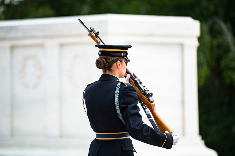 A guard holding a rifle walks by the Tomb of the Unknown Soldier.