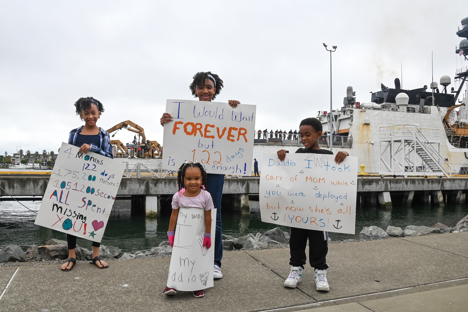 Family members hold signs while they wait for their dad to greet them after the Coast Guard Cutter Bertholf (WMSL 750) and crew returned to homeport in Alameda, Calif., Aug. 3, 2023. The Bertholf deployed for 120-days to the Bering Sea patrol in support of United States national security, U.S. fishing fleet safety and prosperity, and the protection of U.S. living marine resources. (U.S. Coast Guard photo by Senior Chief Petty Officer Charly Tautfest)