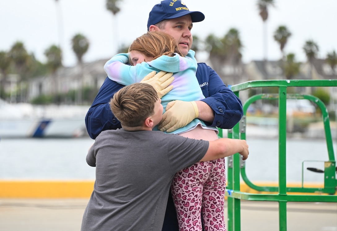 A Coast Guard Cutter Bertholf (WMSL 750) crew member hugs his children after the Bertholf returned to Alameda, Calif., Aug. 3, 2023, following a 120-day Bering Sea patrol. The patrol was in support of United States national security, U.S. fishing fleet safety and prosperity, and the protection of U.S. living marine resources. (U.S. Coast Guard photo by Senior Chief Petty Officer Charly Tautfest)