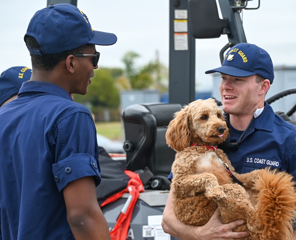 A Coast Guard Cutter Bertholf (WMSL 750) crew member holds his puppy while chatting with friends after the cutter and crew returned to homeport in Alameda, Calif., Aug. 3, 2023. The Bertholf and crew deployed for 120-days for a Bering Sea patrol in support of United States national security, U.S. fishing fleet safety and prosperity, and the protection of U.S. living marine resources. (U.S. Coast Guard photo by Senior Chief Petty Officer Charly Tautfest)