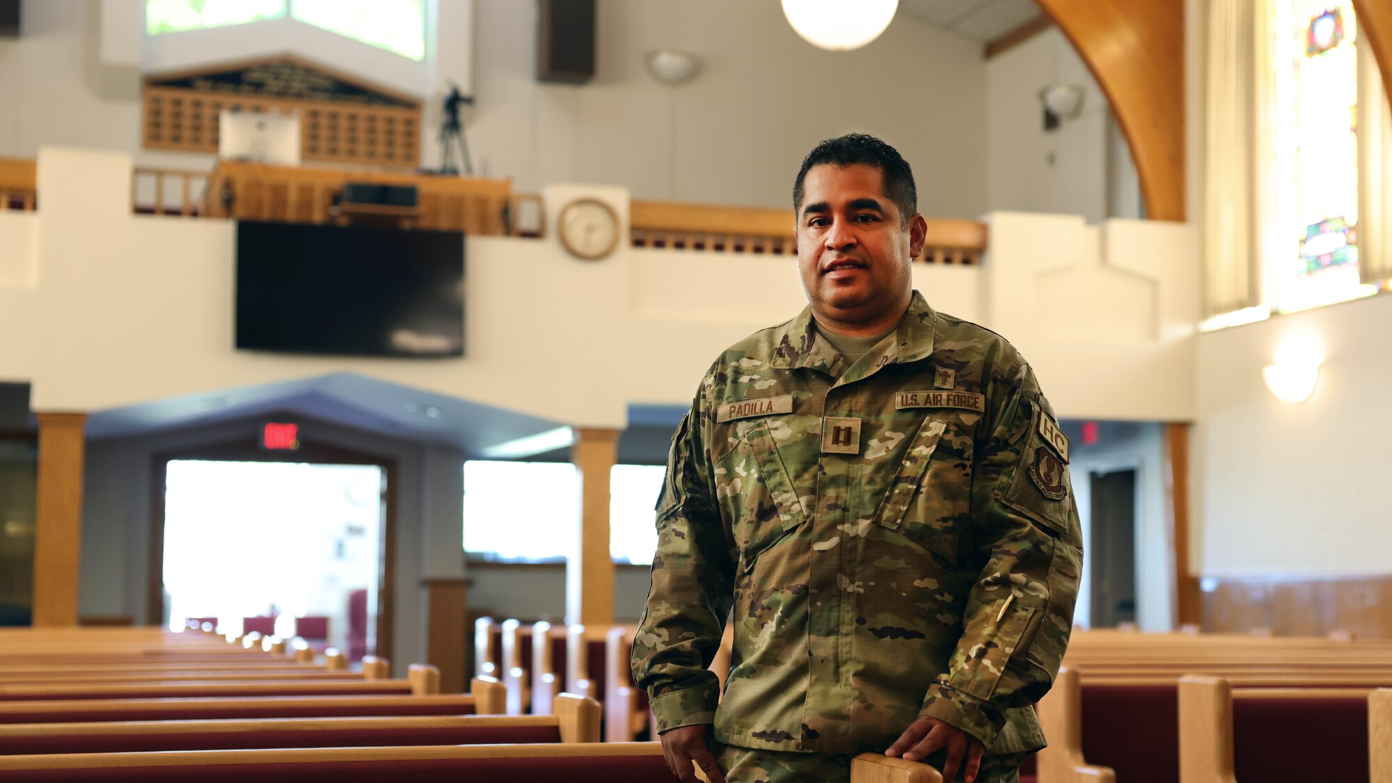 priest stands next to pew