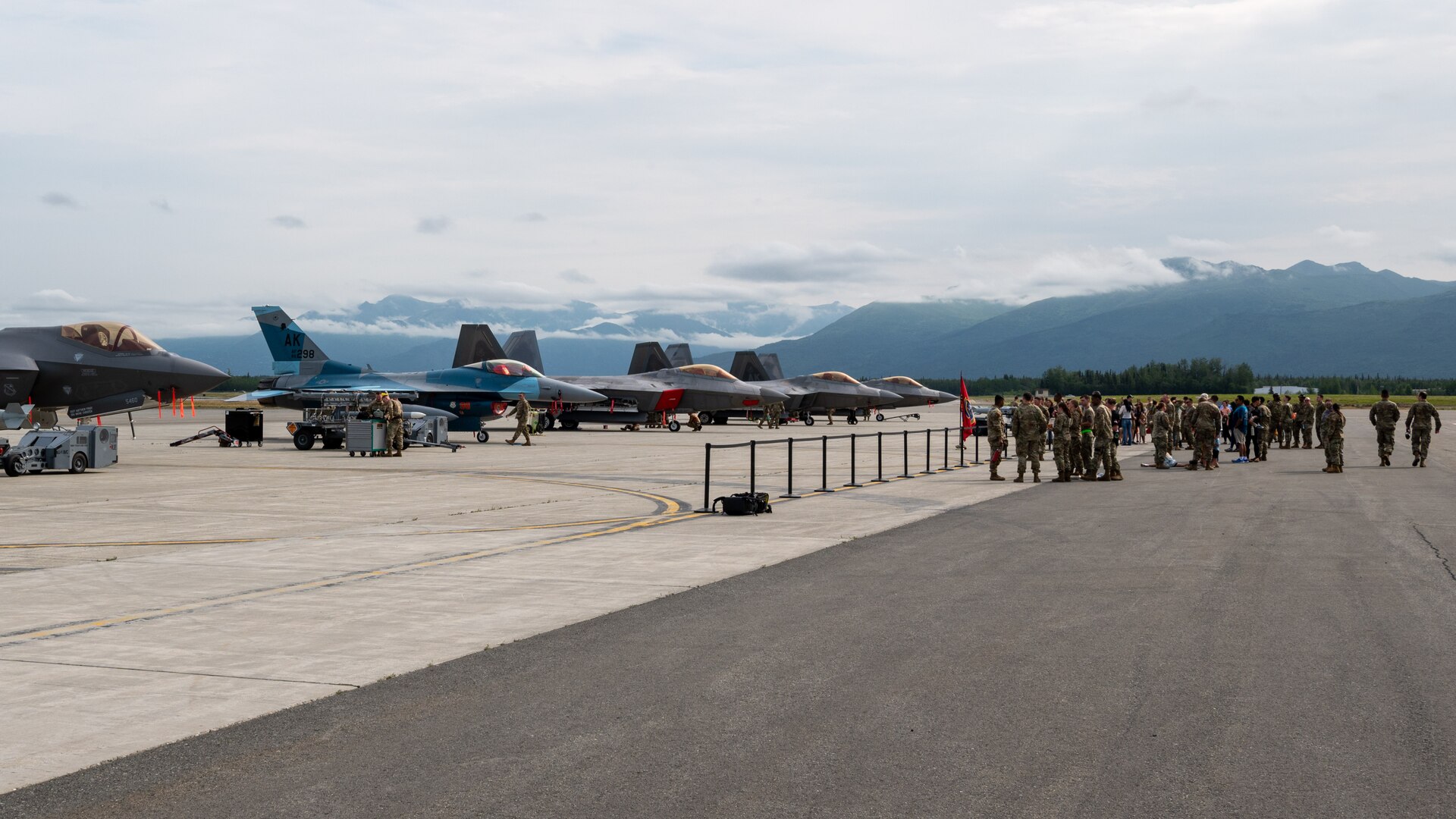 U.S. Air Force aircraft line the runway and the crowd gathers as Airmen prepare the grounds for a load competition at JBER, July 28, 2023