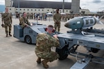 Weapons load team assigned to the 356th Fighter Generation Squadron, Eielson AFB, load a training bomb onto the carrier during a load competition at JBER, July 28, 2023