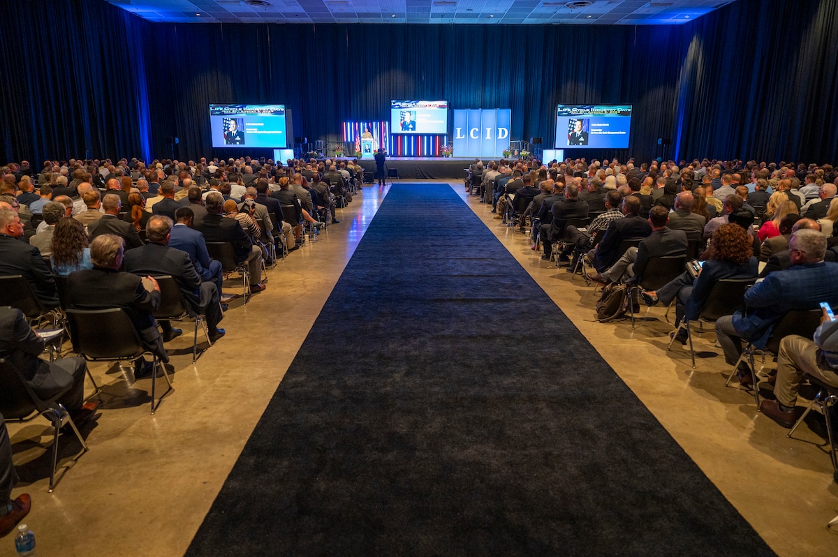 Individuals seated, watching a speaker on stage.