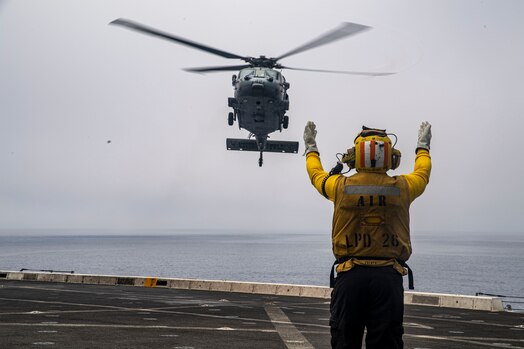  Aviation Boatswain’s Mate (Handling) 3rd Class Marqese Jones directs a MH-60S Sea Hawk helicopter assigned to Helicopter Sea Combat Squadron (HSC) 23 “Wildcards” to the flight deck of amphibious transport dock ship USS John P. Murtha (LPD 26) during Underway Recovery Test (URT) 10, July 26, 2023.