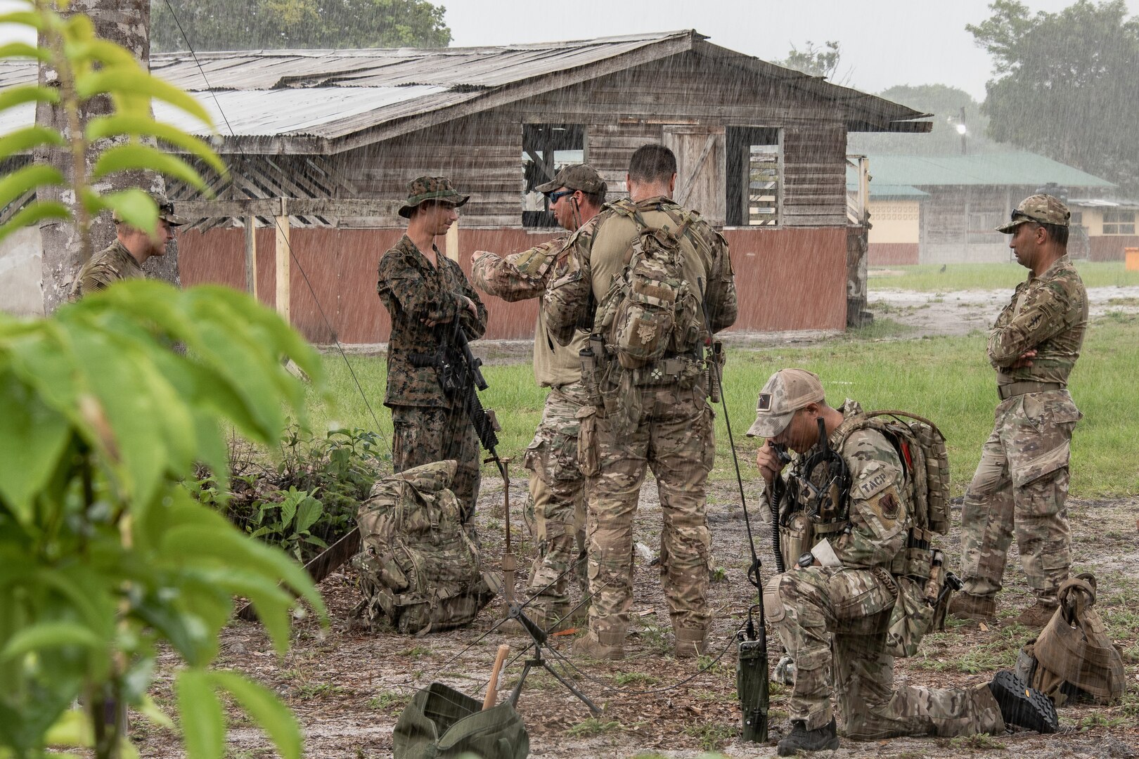U.S. Airmen, Marines and Army Soldiers communicate with radios in the rain