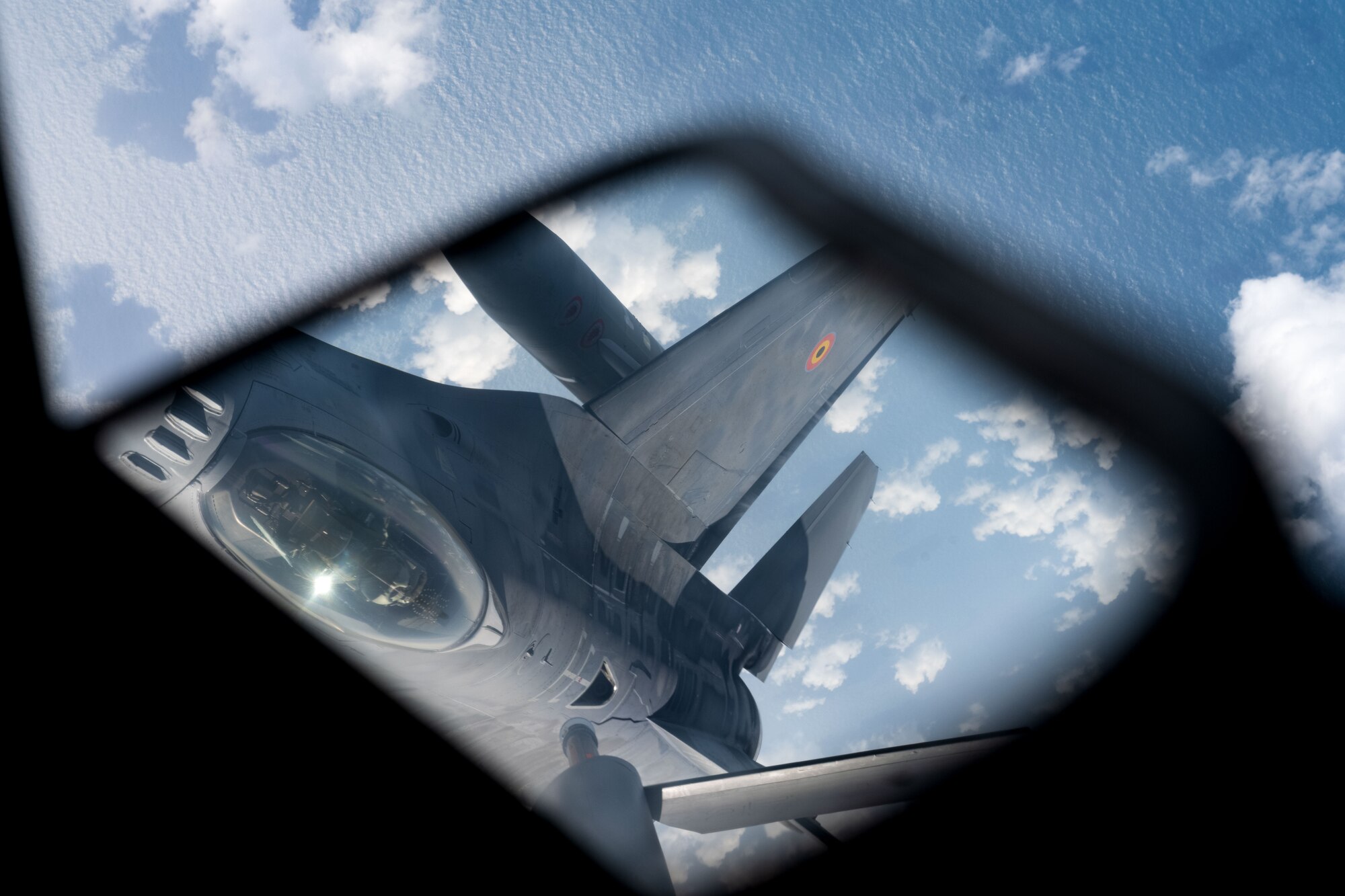 A Belgian Air Force F-16 is seen preparing for an aerial refuel in a reflection above the North Sea