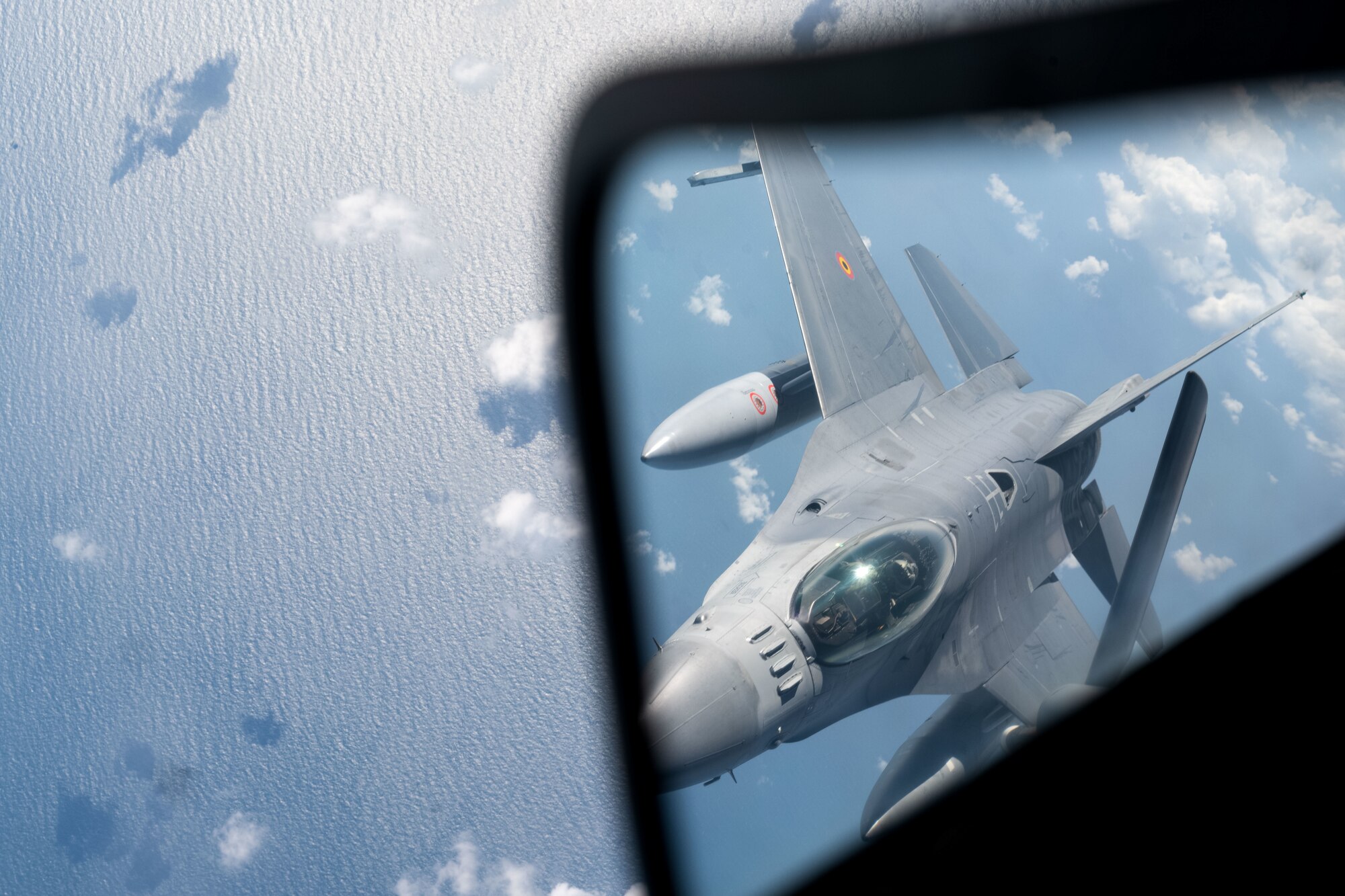 A Belgian Air Force F-16 is seen preparing for an aerial refuel in a reflection above the North Sea