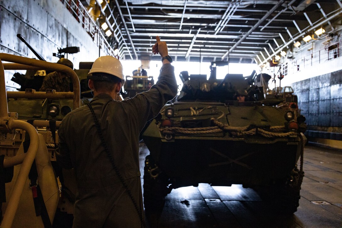 A U.S. Marine assigned to the San Antonio class amphibious transport docking ship USS Mesa Verde (LPD 19) guides a light armored vehicle belonging to the 26th Marine Expeditionary Unit (Special Operations Capable) (MEU(SOC)) onto an LCAC on the Atlantic Ocean, July 25, 2023. The USS Mesa Verde (LPD-19), assigned to the Bataan Amphibious Ready Group and embarked 26th MEU(SOC) under the command and control of Task Force 61/2, is on a scheduled deployment in the U.S. Naval Forces Europe area of operations, employed by U.S. Sixth Fleet to defend U.S., allied and partner interests. (U.S. Marine Corps photo by Cpl. Michele Clarke)